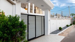 A modern residential building with a closed garage door, a balcony with railings, and a white exterior wall. - Family sized house with a summer hut for outdoor sitting (Tema)