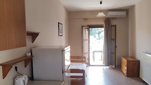 A compact kitchen with a washing machine, a kettle, and a small dining table. - Nikos Apartments A2 in Gialiskari (Ikaria)