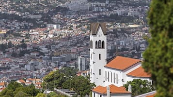 A white church with a clock tower, surrounded by a densely packed urban area with red-tiled roofs.