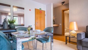 A dining area with a glass table, blue chairs, and a wooden door with emergency exit signs. - Living Funchal by Homie (Funchal)