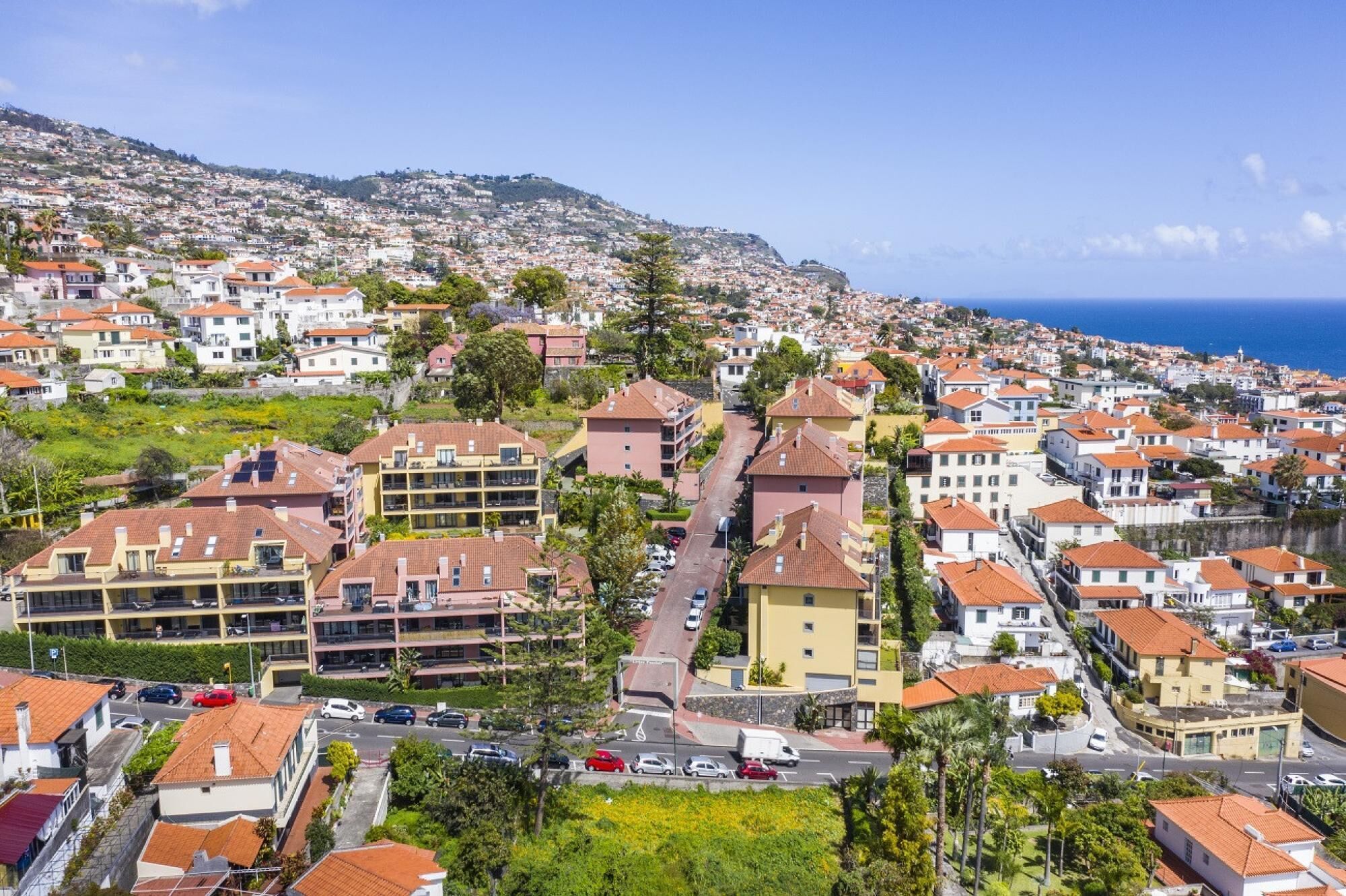 Eine Küstenwohngegend mit Reihenhäusern, einer Hauptstraße und Blick auf das Meer.