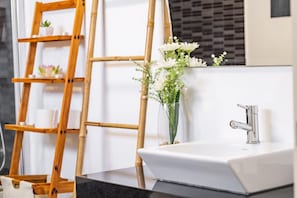 A bathroom with a white sink, a bamboo ladder, and a vase of white flowers. - Uptown Sea View by Homie (Funchal)