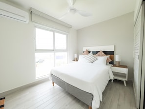 Ein Schlafzimmer mit Bett, Nachttischen, Deckenventilator und Fenster.