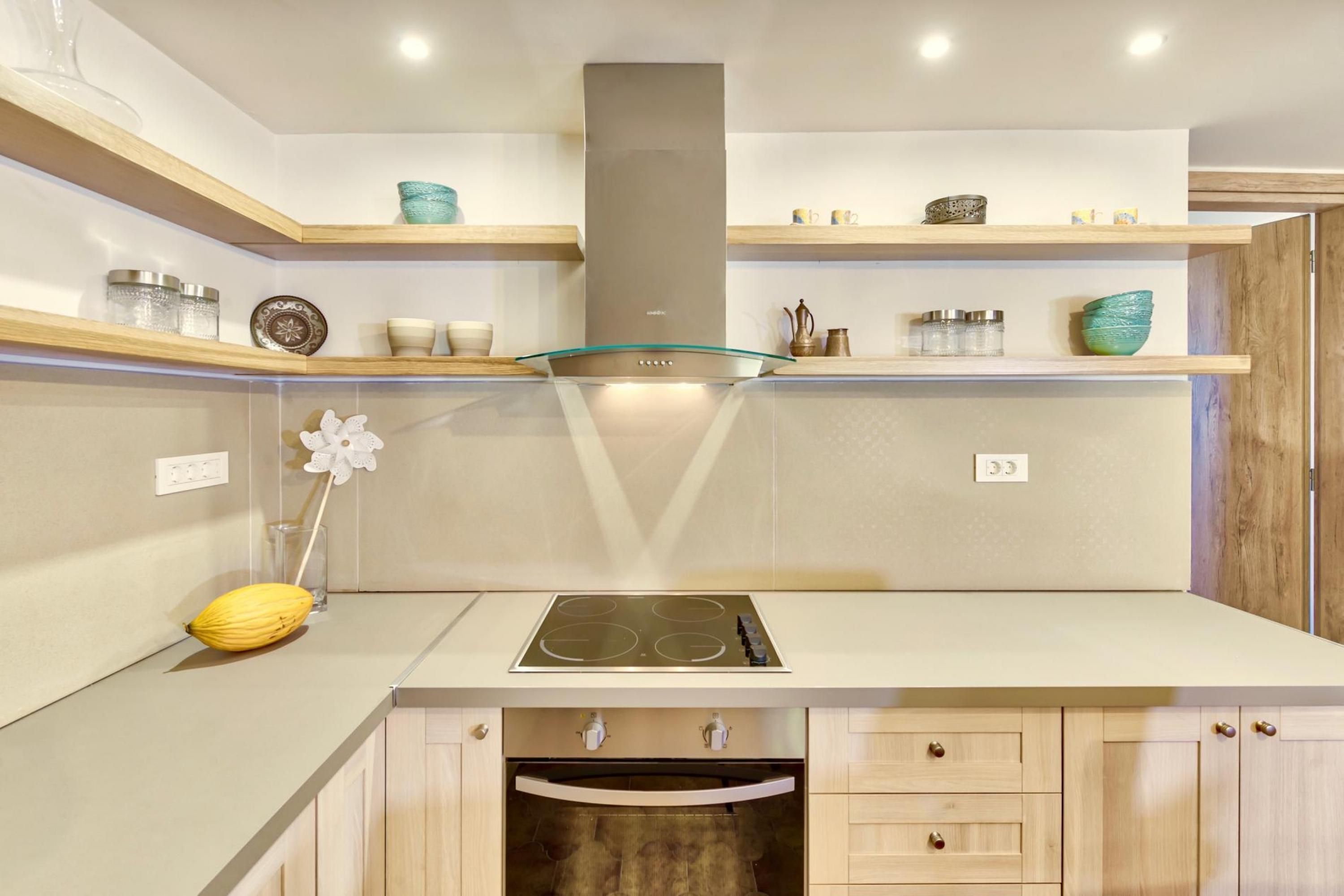 A modern kitchen with a central island, built-in oven, and upper cabinets.