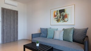 En moderne stue med en grå sofa, et lille sort sofabord og et billede i ramme på væggen.