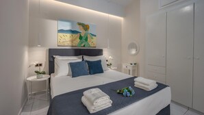 Un dormitorio moderno con una cama grande, paredes blancas, un cuadro sobre la cama y un armario a la derecha.