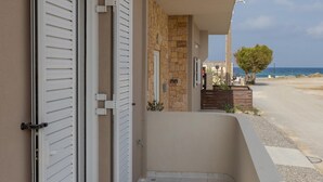 Un balcón con muro de piedra, una puerta y vista al mar.