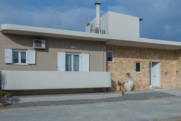 A modern two-story building with a flat roof, a chimney, and a stone facade.