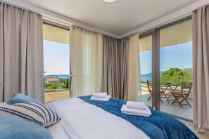 Habitación de hotel con cama, balcón con mesa y sillas, y vista al mar.