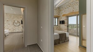 Une chambre d’hôtel avec un mur en pierre, un lit, une télévision et un balcon avec vue.