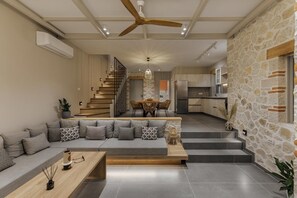 Uma sala de estar moderna com um sofá, mesa de centro e uma escada que leva a uma área de refeições.