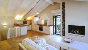 Un amplio salón con techo alto, una cocina con electrodomésticos modernos y una chimenea.