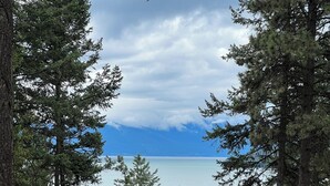 Une vue d’un lac entouré d’arbres, avec une route et un bâtiment en arrière-plan.