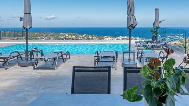 A poolside area with lounge chairs and umbrellas, overlooking a coastal landscape. - Villa Eagles - With Private Pool (Rethymno)