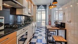 A compact kitchen with a checkered floor, a stove, a sink, and a small dining table with benches. - Nomad s Chiado Lisbon - The Ivens Signature (Lisbon)