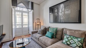 A living room with a sofa, a coffee table, and a large framed picture on the wall. - Nomad s Chiado Lisbon - The Ivens Signature (Lisbon)