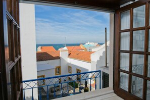 A balcony with a view of the sea and buildings with red-tiled roofs. - Casa do Pescador by Acasadascasas (Mafra)