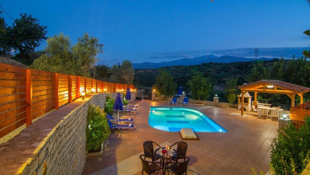 A swimming pool with lounge chairs and a covered seating area, surrounded by a stone wall and vegetation. - Blue Villa 1 - With Private Pool (Mylopotamos)