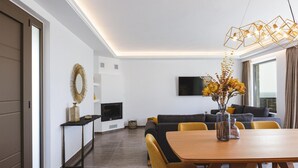 Un salon moderne comprenant un canapé, un téléviseur et un coin repas avec une table et des chaises.