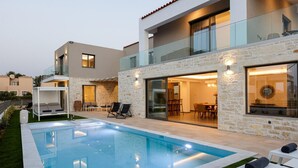 Une maison moderne dotée d’une piscine, d’un espace salon extérieur et d’un coin repas.
