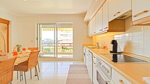 A modern kitchen with a dining area, large windows, and a view of the city.