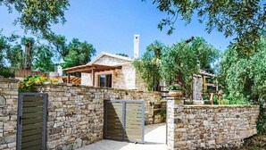 A stone-walled property with a stone gate, a covered patio, and a stone chimney. - Aristea - 2 BR Villa Surrounded by Olive Groves (Paxos)