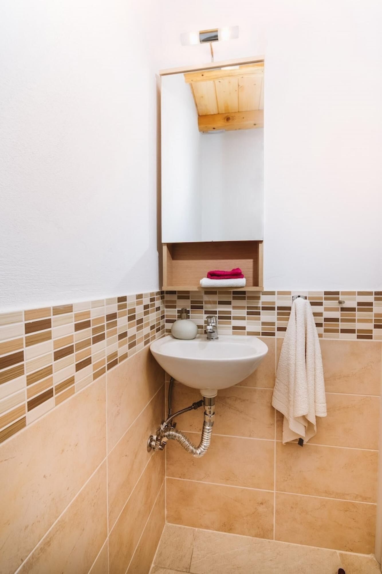 Une salle de bain avec un lavabo blanc, un miroir et un porte-serviettes.