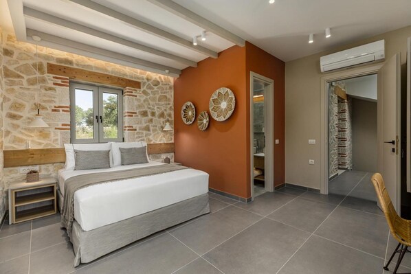 A bedroom with a stone wall, a bed, a nightstand, and a chair.