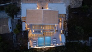 An aerial view of a modern hotel with a central courtyard, a swimming pool, and multiple guest rooms. - Armonia II Villa in Paxi (Paxos)