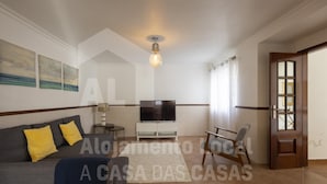 A living room with a sofa, TV, and a chair. - White House by Acasadascasas (Mafra)