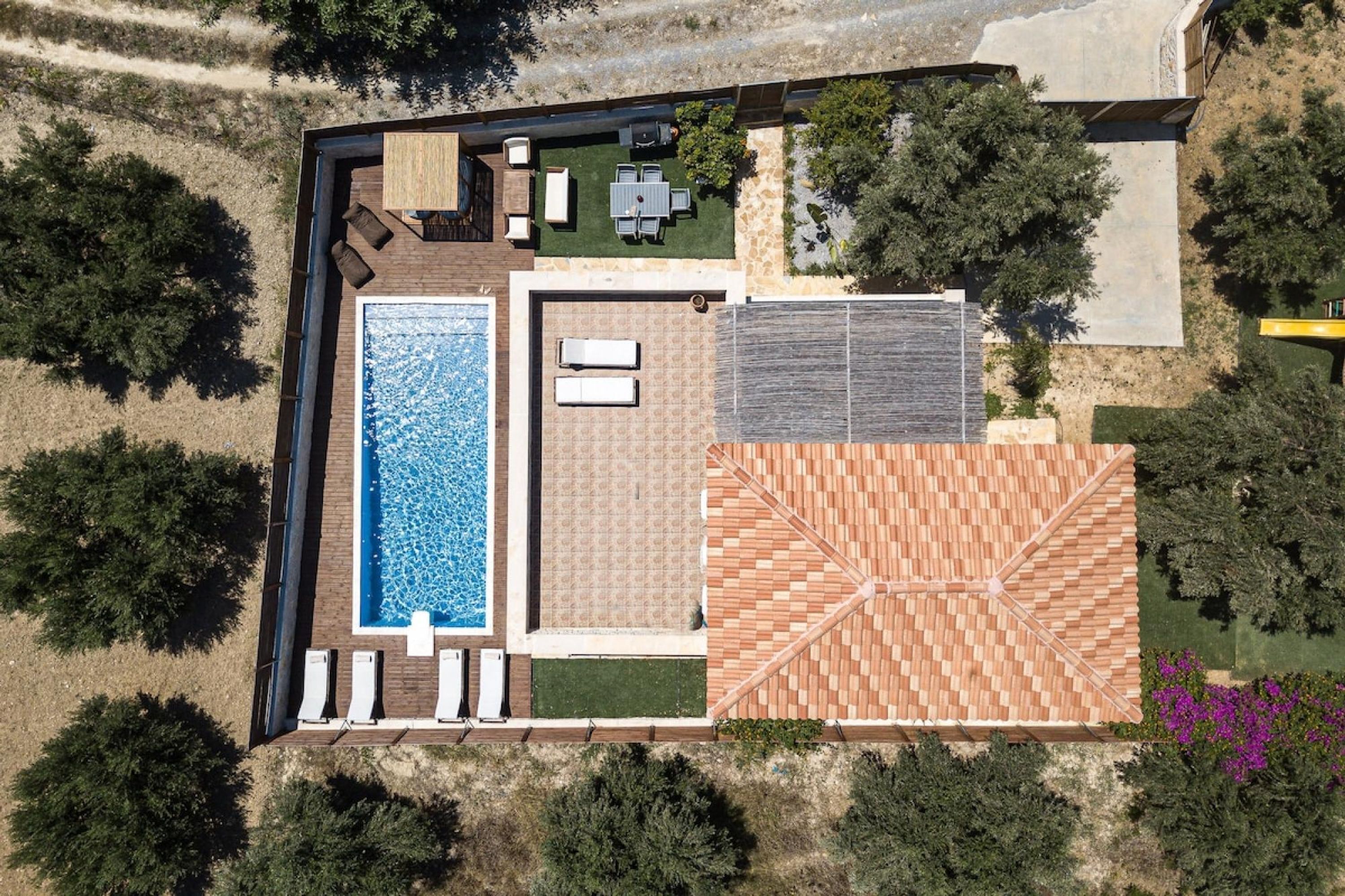 An aerial view of a property with a swimming pool, a patio area with seating, and a covered patio space.