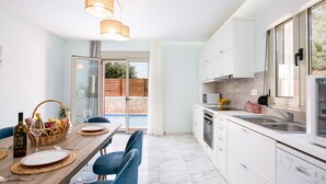 A modern kitchen with white cabinets, a built-in oven, and a large window. - Villa Vera - With Private Pool Jacuzzi (Rethymno)