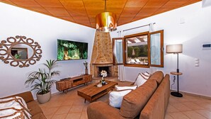 Una sala de estar con chimenea, techo de madera y un ventanal grande.