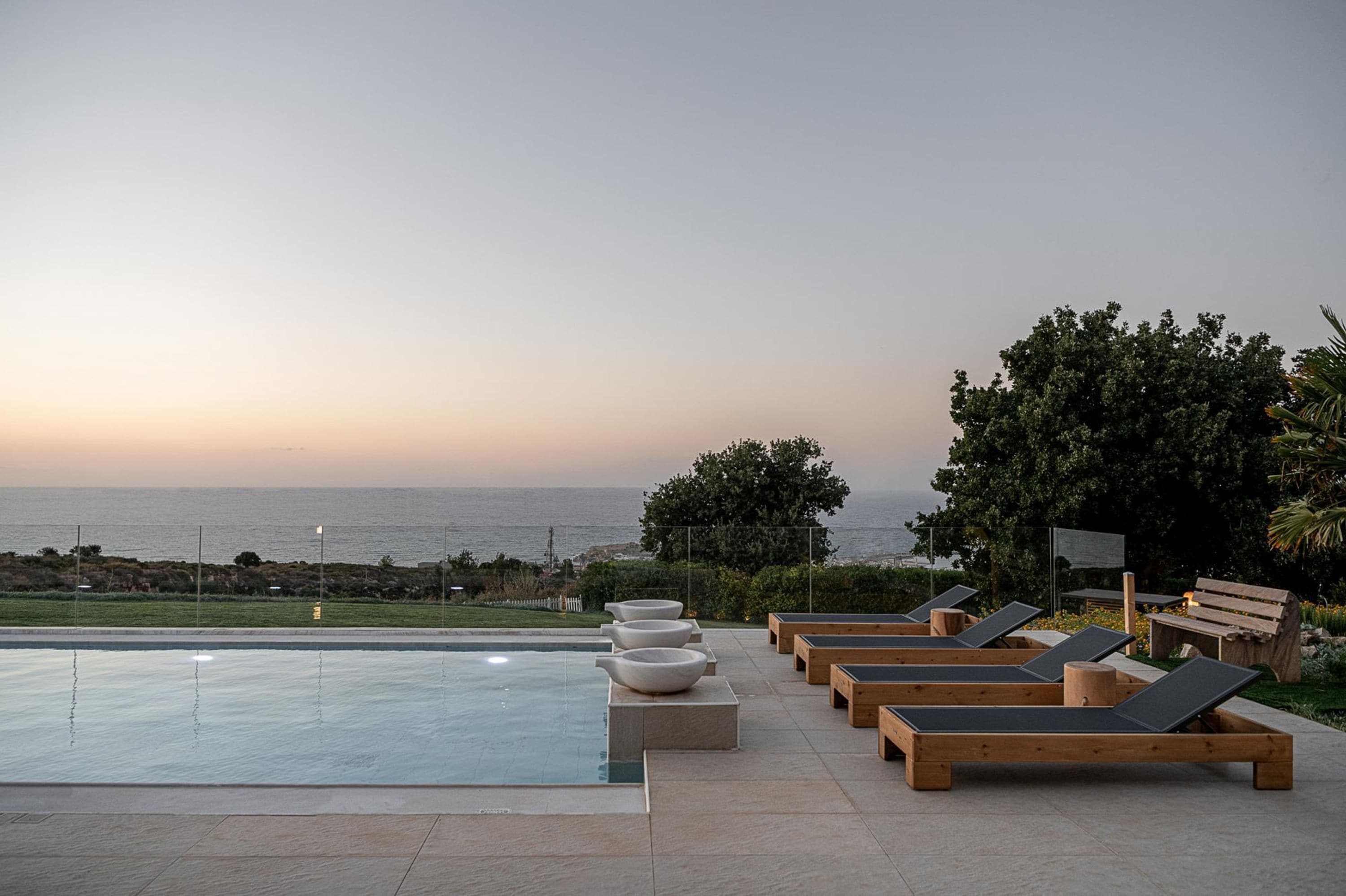A poolside area with lounge chairs and a view of the ocean.