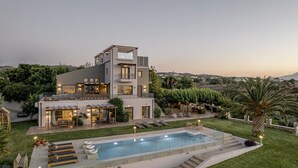 Uma casa moderna de dois andares com piscina, área de estar externa e um jardim bem cuidado.