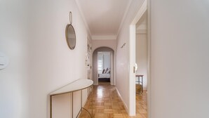 A hallway with a white wall, a round mirror, and a wooden floor. - Nomad s By Sta Catarina Flats - 3bed Moments (Porto)