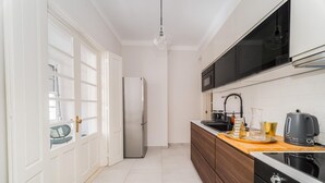 A modern kitchen with white cabinetry, a stainless steel refrigerator, a black stove, and a wooden countertop. - Nomad s By Sta Catarina Flats - 3bed Moments (Porto)