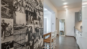 A modern kitchen with white cabinets, a dining area with a wooden table and chairs, and a wall decorated with black and white photographs. - Top Centre Apartment Next to Vitosha Boulevard (Sofia)