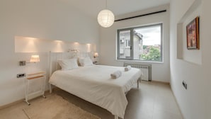 A bedroom with a large bed, bedside lamps, a radiator, a window with a view, and a wall-mounted picture. - Top Centre Apartment Next to Vitosha Boulevard (Sofia)