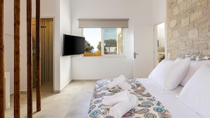 Een moderne hotelkamer met een groot bed, een flatscreen televisie, een raam met uitzicht en een stenen muur.