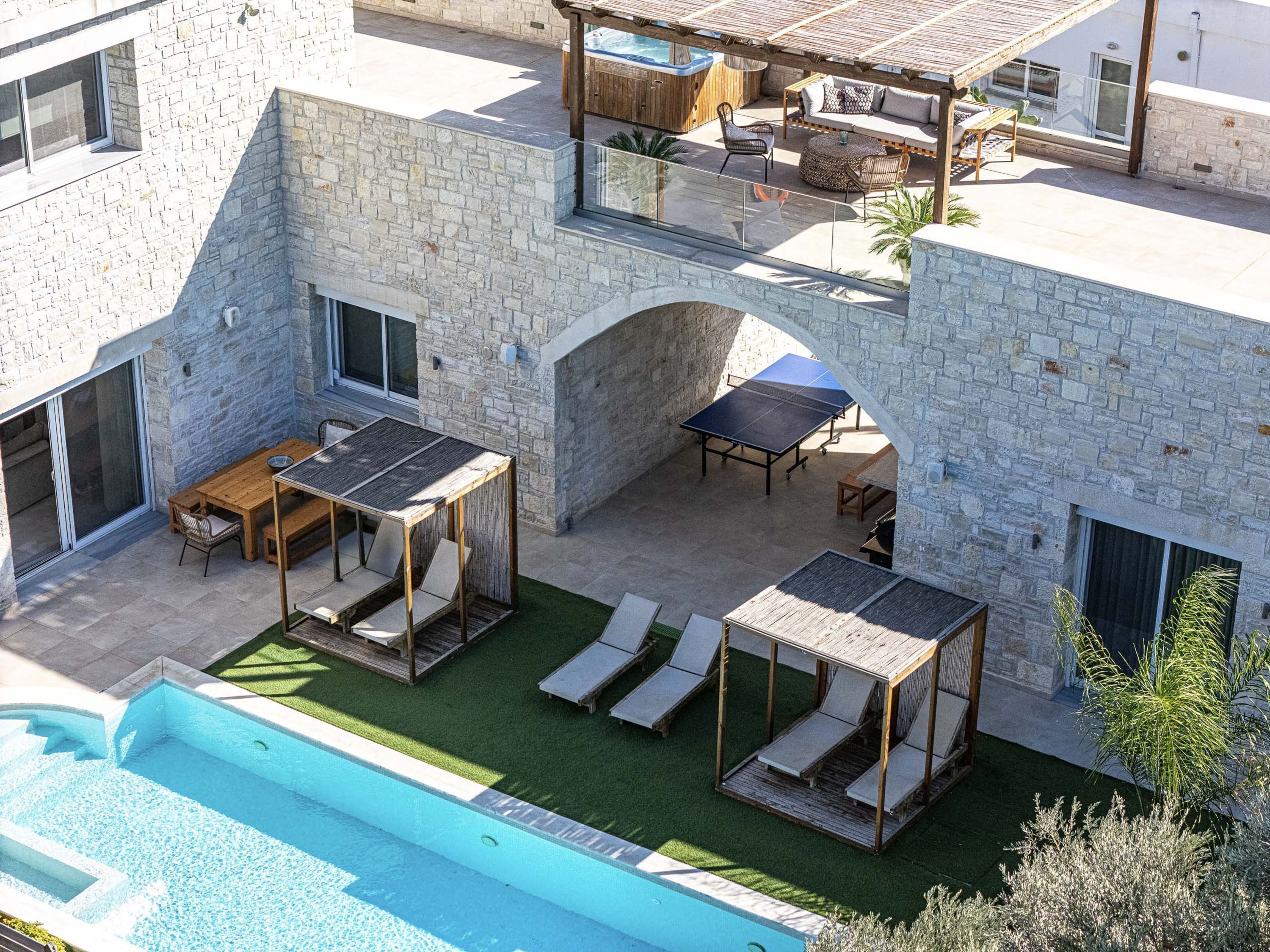 Edifício de pedra com piscina, área de estar ao ar livre e hidromassagem.