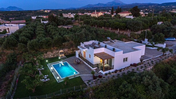 A modern two-story house with a swimming pool, surrounded by trees and a mountainous backdrop. - Villa Guinevere-with Private Pool (Rethymno)