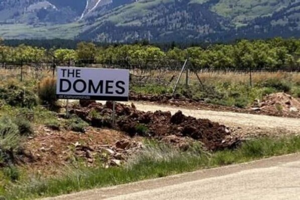 Ein Schild mit der Aufschrift 'The Domes' vor einer Bergkulisse.