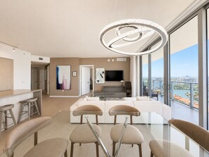 A modern living room with a large window, a dining area with bar stools, and a flat-screen TV mounted on the wall. - ★★★★★MILLION APART 2BD. 1MIN TO BEACH - no resort & parking fee, check details (Hollywood)