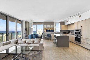 Un apartamento moderno con sala de estar, cocina y grandes ventanales que ofrecen vistas a la ciudad.