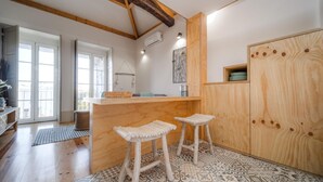 A kitchen with wooden stools, a wooden counter, and a patterned floor. - Bonjardim City Flats - Top Floor (Porto)