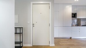 A modern kitchen with white cabinets, a wooden floor, and a door with a handle. - Nomad s Family - 2bdr Sunny Firmeza (Porto)