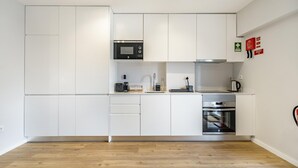 A modern kitchen with white cabinets, a microwave, a coffee maker, and a built-in oven. - Nomad s Family - 2bdr Sunny Firmeza (Porto)