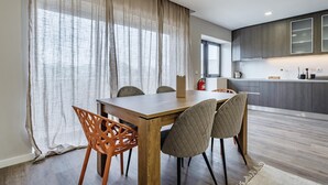 Een moderne keuken met donkere kastjes, een houten eettafel en vier stoelen.