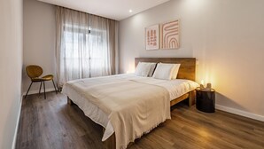 Een slaapkamer met een groot bed, een stoel en een nachtkastje met een lamp.